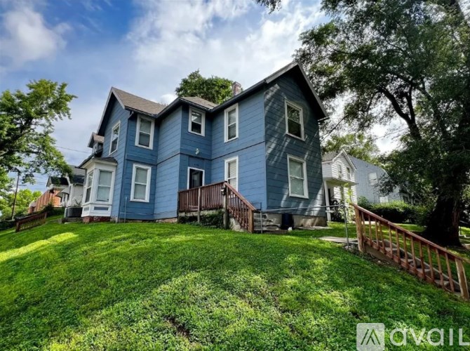 A blue house with a white fence and a green lawn.
