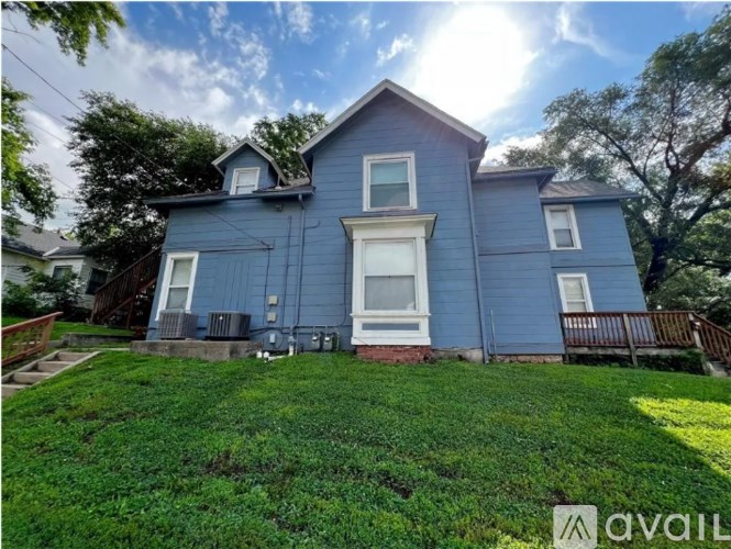 A blue house with a white window and a green lawn in front.