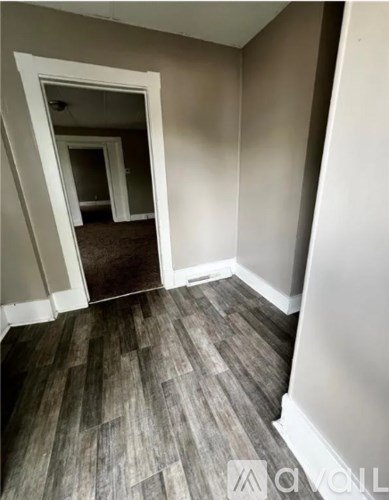 A hallway with a wooden floor and white walls.