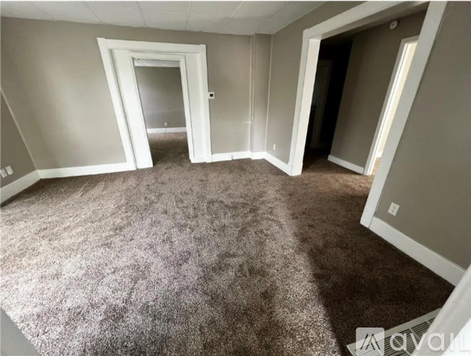 A room with carpeted floor and two open doors.