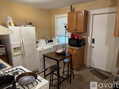 A kitchen with a white refrigerator, a stove, a microwave, and a dining table with two chairs.
