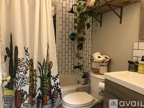 A bathroom with a toilet, sink, and a shower curtain with a cactus design.