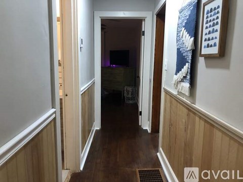 A hallway with a door on the left and a painting on the right.