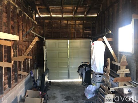 A man in a white shirt is standing in a garage with a white door.
