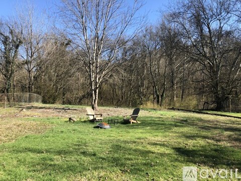 A picnic table sits in a grassy field with trees in the background.