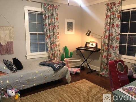 A room with a bed, desk, and window with curtains.