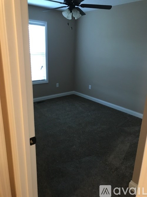 A room with a ceiling fan and a window.