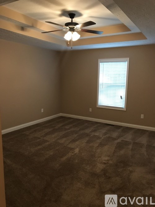 A room with a ceiling fan and carpeted floor.