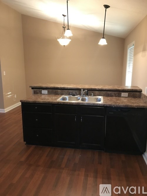 A kitchen with black cabinets and a granite countertop.
