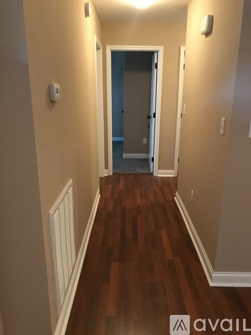 A hallway with wood floors and white walls.