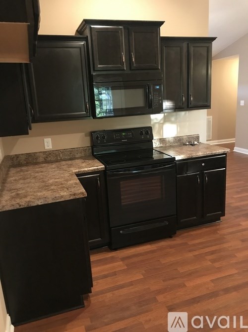 A kitchen with black cabinets and a granite countertop.