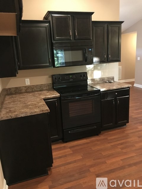 A kitchen with black cabinets and a granite countertop.