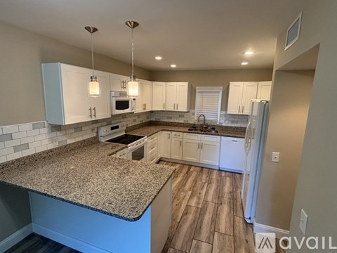 A kitchen with granite countertops and white cabinets.