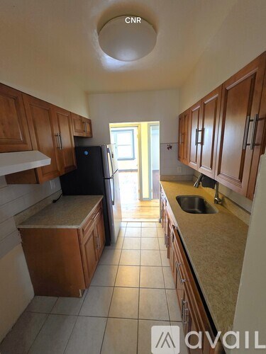 A kitchen with wooden cabinets and a black refrigerator.