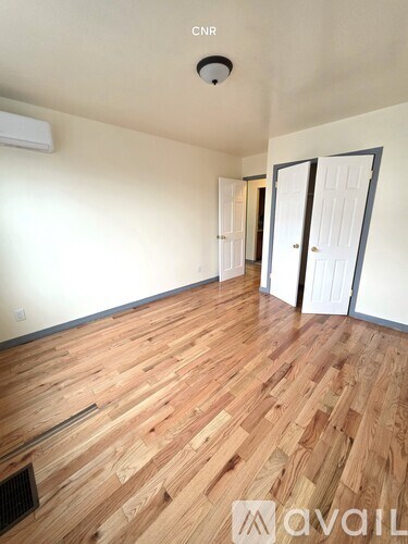 A room with wooden flooring and two doors.