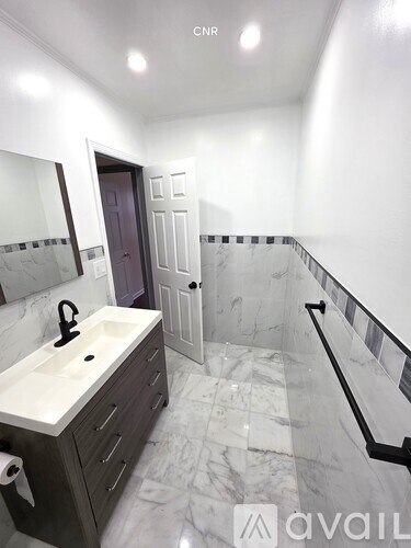 A bathroom with a marble floor and a sink with a black faucet.