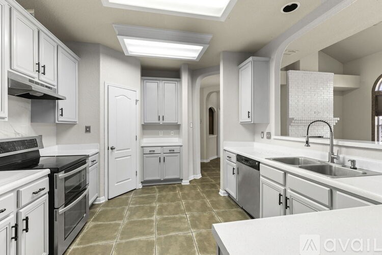 A kitchen with white cabinets and a tile floor.