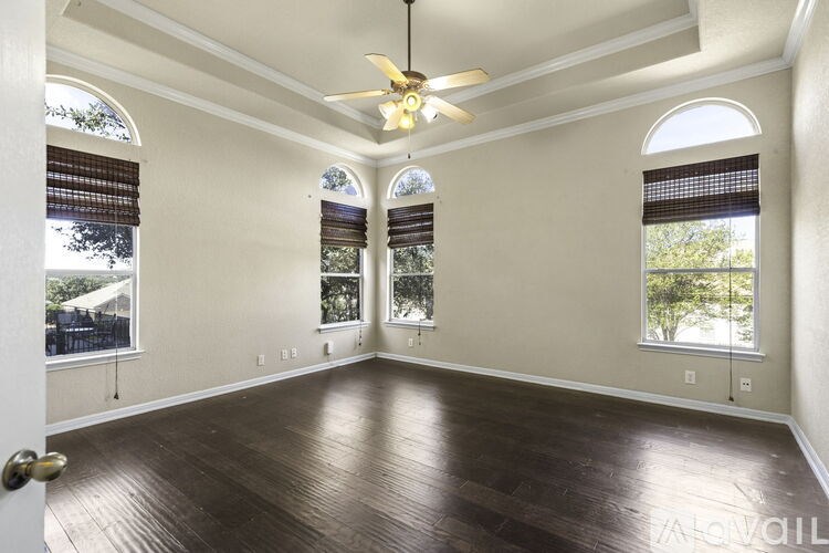 A room with a ceiling fan and wooden flooring.