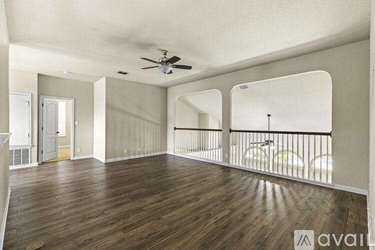 A spacious room with wooden floors and a balcony with a railing.