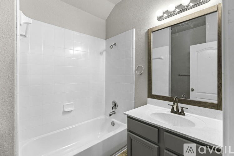 A white bathroom with a tub, sink and mirror.
