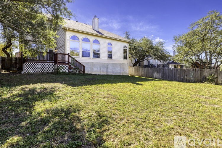 A yellow house with a black fence and a green lawn.