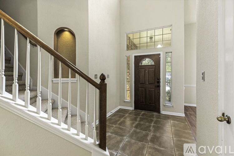 A hallway with a wooden staircase and a black door.