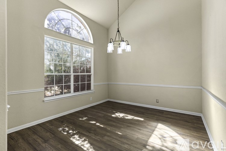 A spacious room with a fireplace and three arched windows.