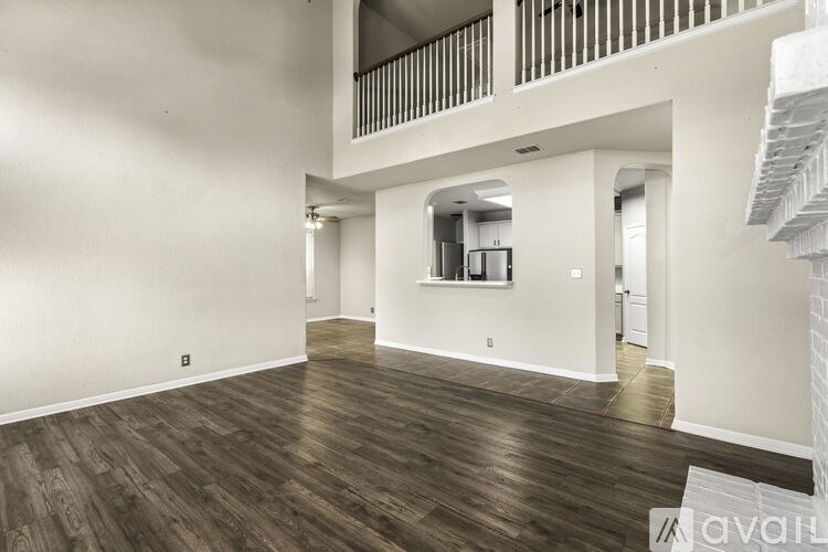 A spacious living room with wooden flooring and white walls.