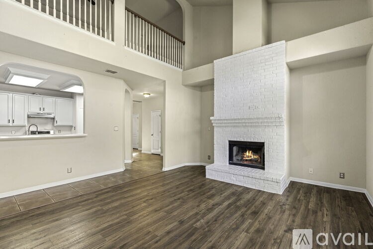 A large, empty living room with a fireplace and wooden floors.