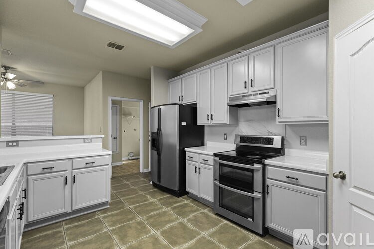 A kitchen with white cabinets and a black refrigerator.