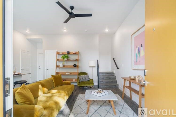 A living room with a yellow couch and a fan on the ceiling.