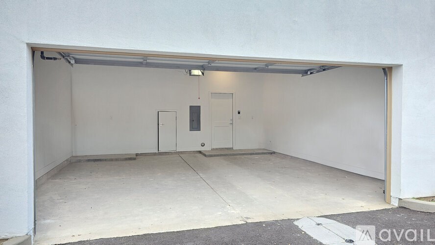 A large white garage with a door and a wall on the side.