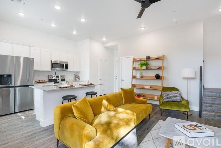 A modern living room with a yellow sofa and a kitchen in the background.