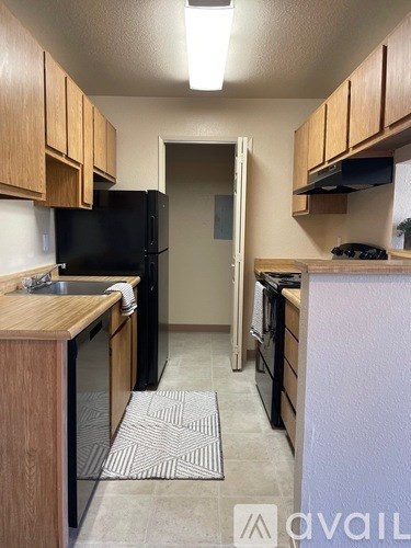 A kitchen with wooden cabinets and a black refrigerator.
