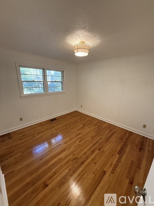 A room with wooden flooring and a window.