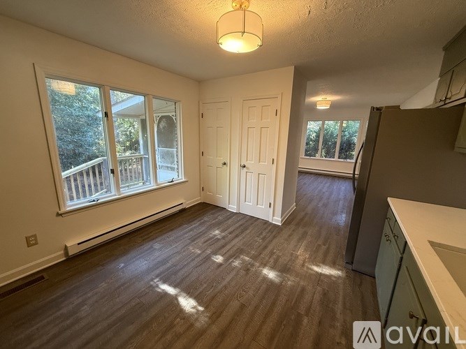 A room with wooden flooring and a large window with a view of a balcony.