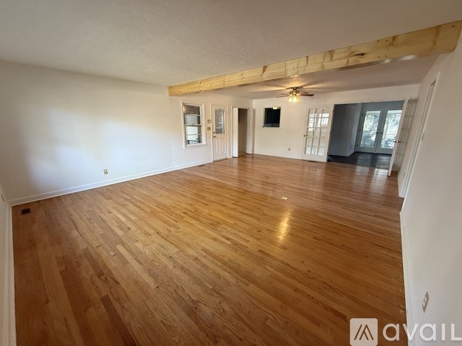 A spacious room with wooden flooring and a ceiling fan.