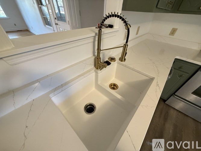 A white sink with a gold faucet in a marble bathroom.