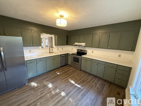 A kitchen with wooden floors and green cabinets.