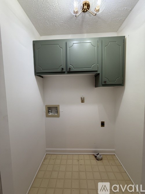 A small room with green cabinets and a tiled floor.