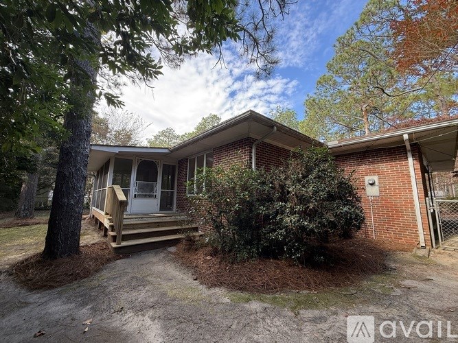 A house with a porch and a tree in front of it.
