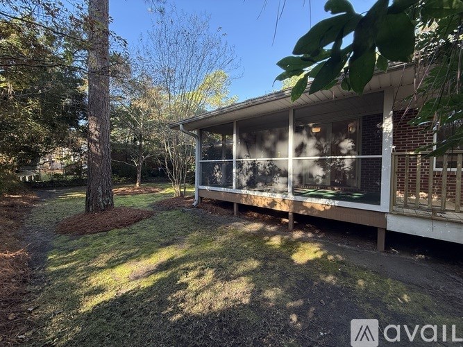 A house with a porch and a tree in front of it.