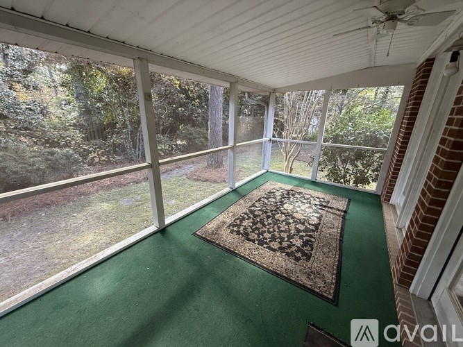 A sunroom with a green floor and a rug in the middle.