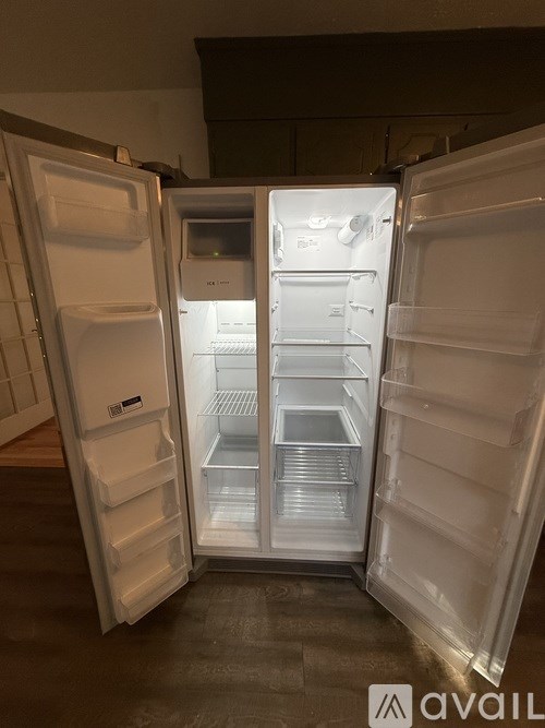 Three white refrigerators are open and empty.
