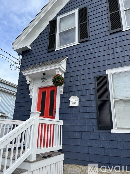 A blue house with a red door and a window with black shutters.