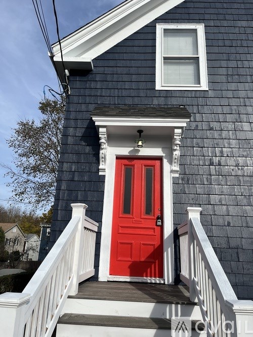 A blue house with a red door and white railings.