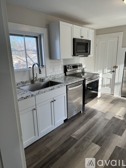 A kitchen with white cabinets and a black microwave.