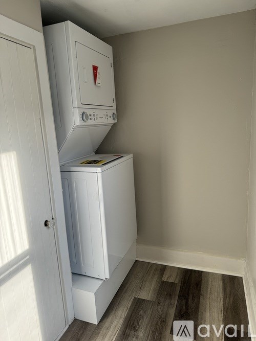 A white mini fridge is in a corner of a room with a wooden floor.