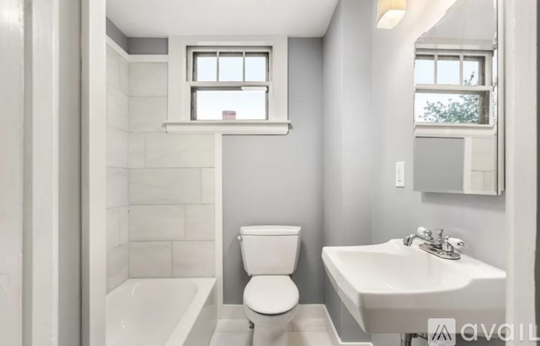 A white toilet sits in a bathroom next to a sink and a bathtub.