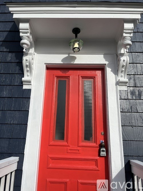 A red door with a white frame and a black roof above it.